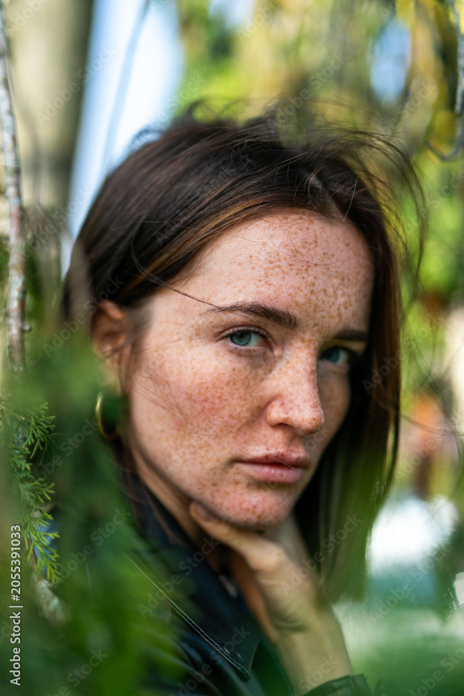 Naklejka premium Woman with freckles and brown hair in a natural outdoor setting.