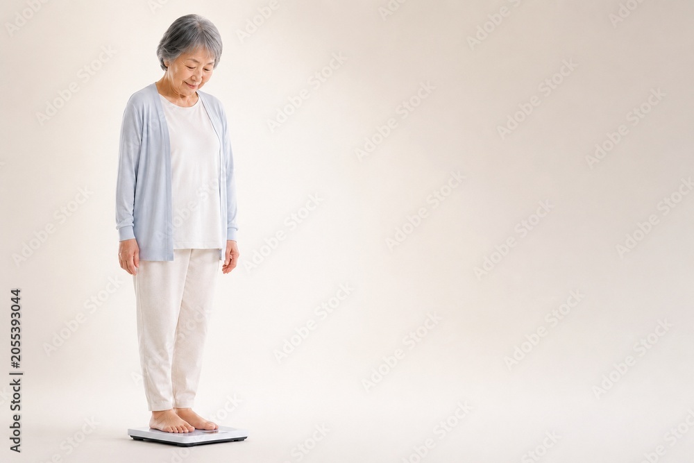 Fototapeta premium Senior Japanese woman checking her weight, mid shot