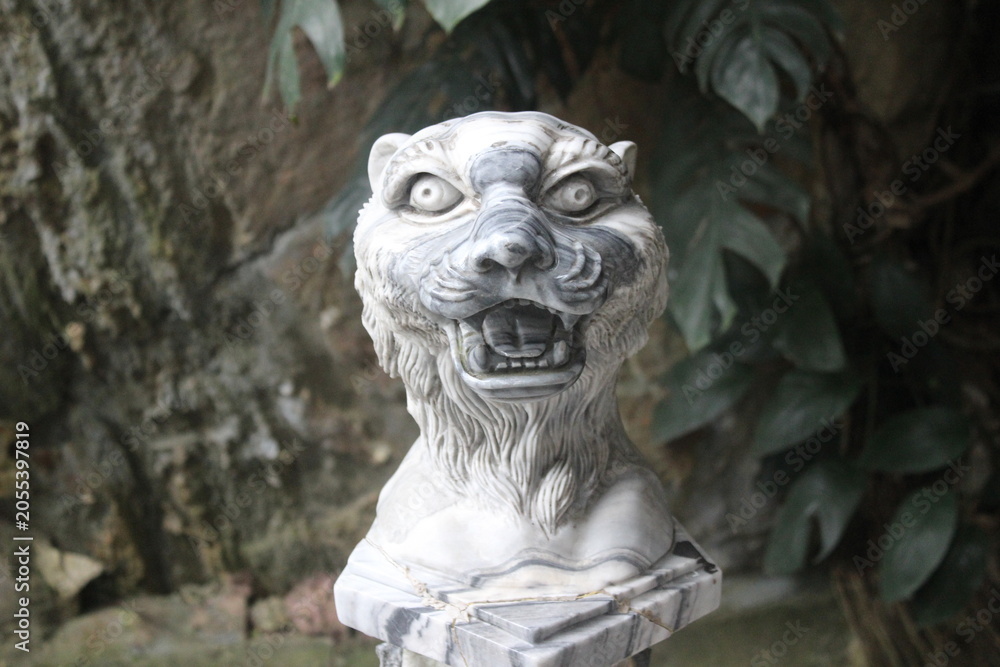 Obraz premium Ferocious tiger head sculpture carved from white marble on a stone base platform.