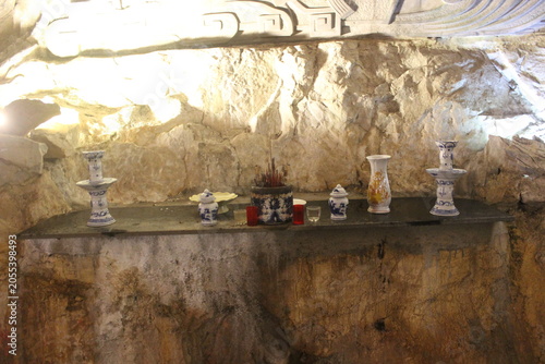 Фотография Religious altar with vases and offerings on shelf in illuminated cave