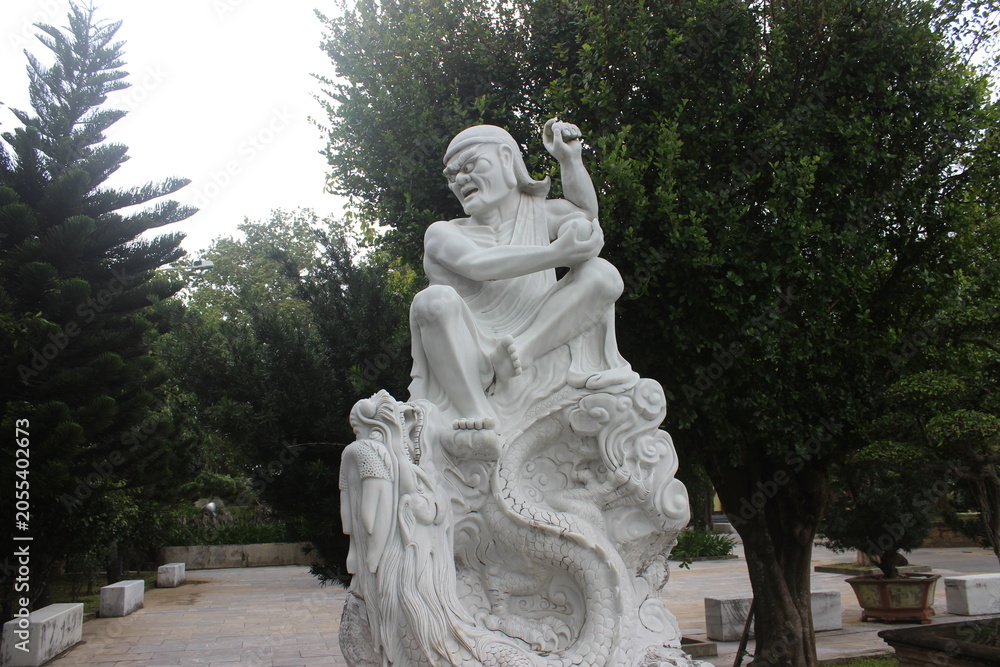 Obraz premium White marble sculpture of seated man resting on back of large mythical dragon beast.