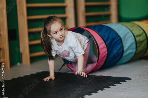 Foto A young girl crawls through a colorful play tunnel during a kids fitness activity
