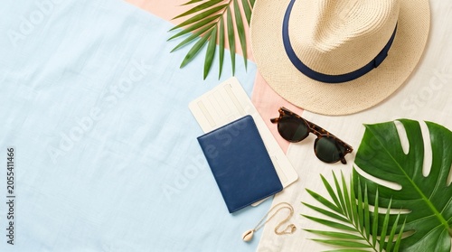 Blue passport with flight boarding pass tickets on a colorful pastel background. Flat lay summer travel concept with straw hat, sunglasses, and palm leaves.
