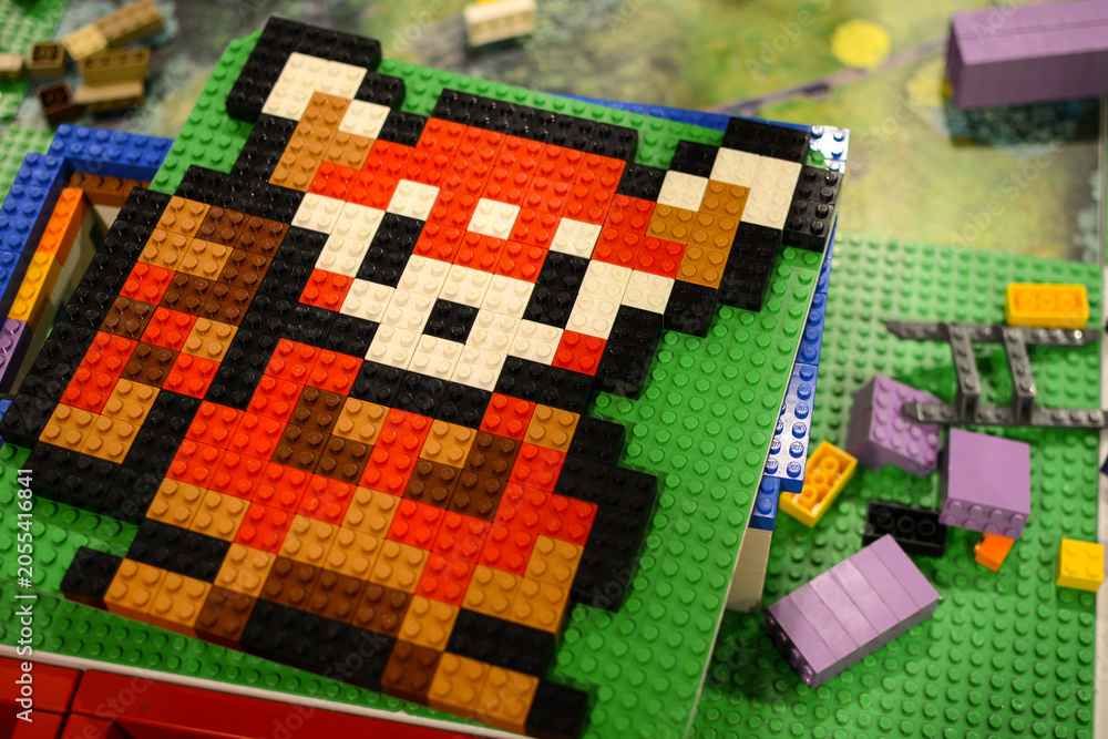 Naklejka premium A Lego bear on a board against a background of multi-colored Lego bricks. Poland. Warsaw.