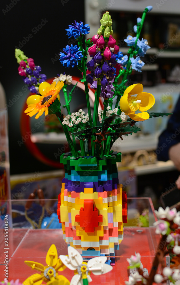 Naklejka premium A bouquet of Lego flowers against a background of multi-colored Lego bricks.