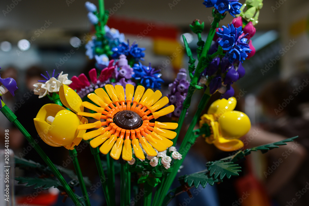 Naklejka premium A bouquet of Lego flowers against a background of multi-colored Lego bricks.
