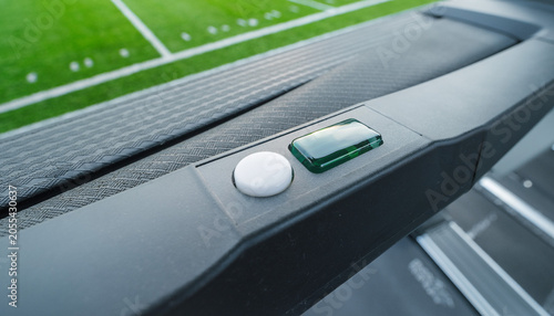 A treadmill’s green switch stares back, a quiet portal at the edge of the indoor field