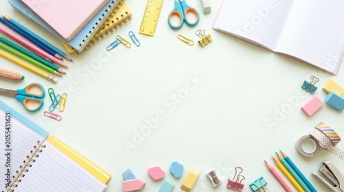 Colorful school stationery border frame layout on bright background for back to school promotion. Flat lay mockup of notebooks, pencils, and scissors.