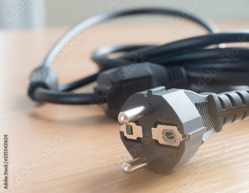 A sleeping serpent of electricity rests on the desk, its plug like a silent mask