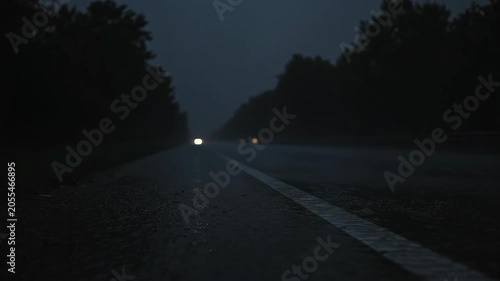 Night driving in heavy rain headlights illuminating stormy road and dark trees
