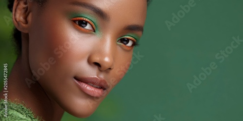 a beautiful, dark skinned woman with green skin, wearing green and orange makeup
