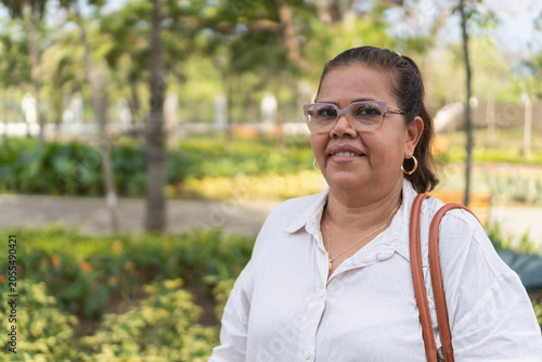 Mature woman wearing eyeglasses smiling reflecting serenity in park