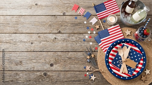 Fourth of July picnic table setting with american flags and party decorations.