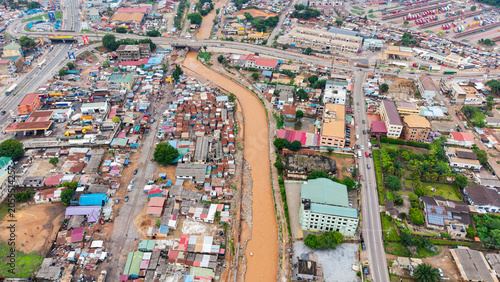 Fotografi Aerial view, Accra Ghana dense urban landscape showing a muddy storm drain flowi