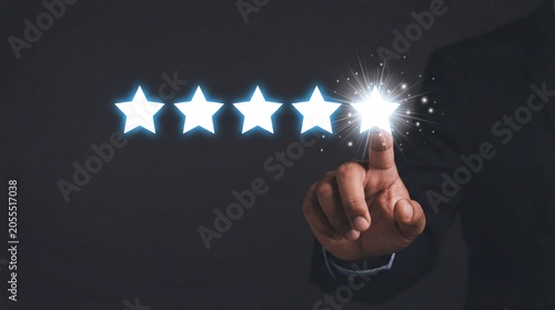 Person clicking fifth star in glowing rating system on dark background, showcasing digital stars while star rating for modern business & office
