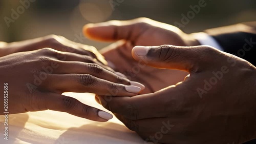 Close up of diverse couple holding hands with light reflecting on skin and formal attire