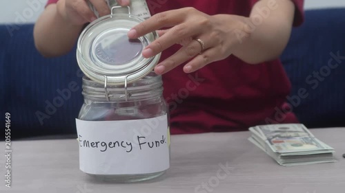 Woman Counting Cash Money and Putting US Dollar Bills Into Emergency Fund Jar