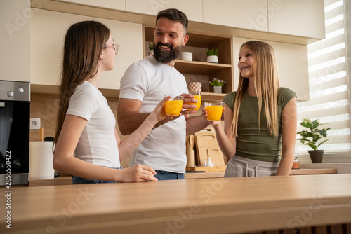 Dad and daughters sharing juice toast in warm home kitchen moment