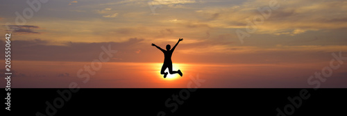 Fotografija A silhouette of a person jumping for joy against a vibrant sunset sky