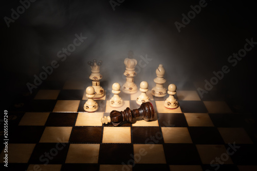 Canvastavla Dark chess king fallen on chessboard among white pieces in dramatic smoke