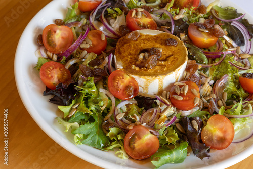 Goat cheese salad with cherry tomatoes, red onion, sunflower seeds and honey soy dressing