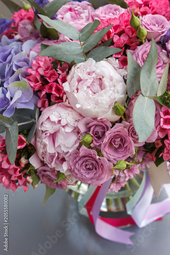 Close-up of bouquet with white peonies, mauve spray roses, pink stock, hydrangea and eucalyptus in glass vase - romantic pink-purple floral detail