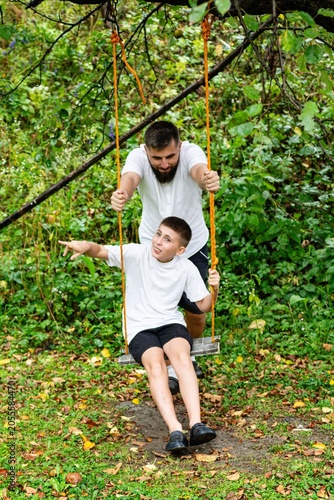 Father and son enjoying a fun swing ride outdoors on an autumn day.