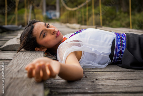 Young indigenous otavalo woman lying on a wooden bridge