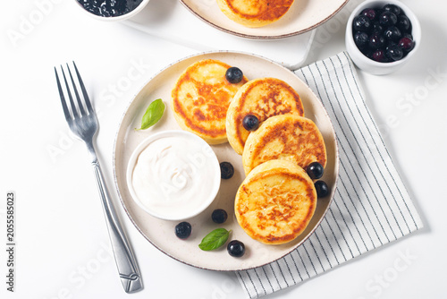 Traditional cottage cheese pancakes served with sour cream, blueberry jam and fresh berries. Healthy and protein breakfast concept. 