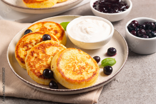 Traditional cottage cheese pancakes served with sour cream, blueberry jam and fresh berries. Healthy and protein breakfast concept. 