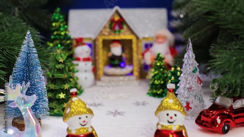 Against the backdrop of a Christmas house with a gnome on the porch, snowmen with Christmas trees and a deer with a red car