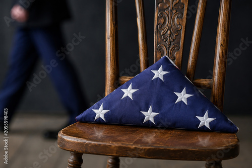 Fotografie Folded american flag resting on vintage wooden chair for memorial day remembrance or solemn tribute