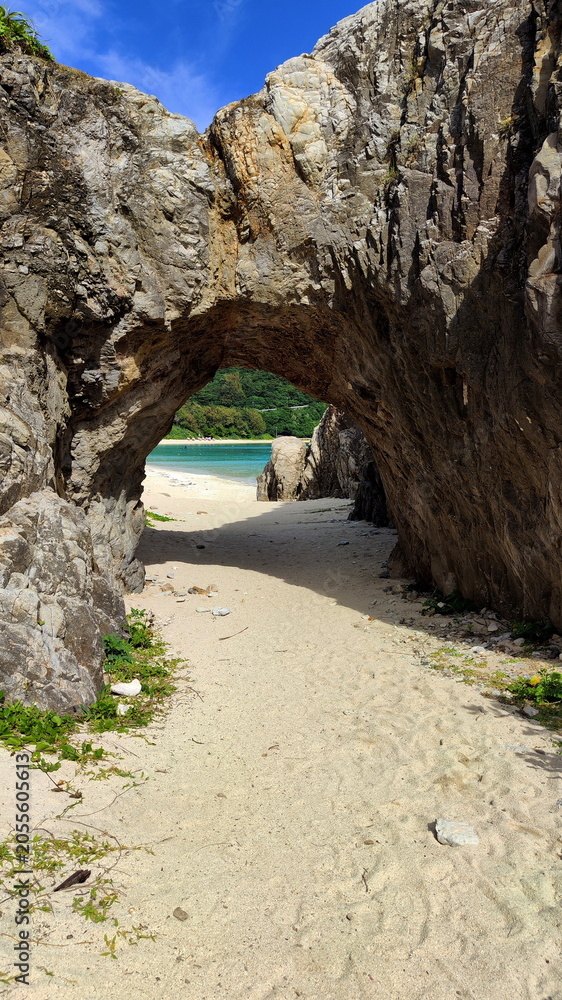 Fototapeta premium Natural arch in a massive rock overlooking the beach.