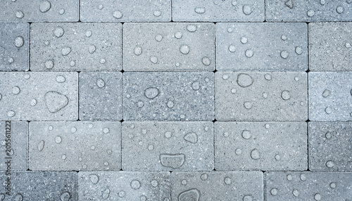 Close up view of gray paving stones covered with fresh rain water droplets.