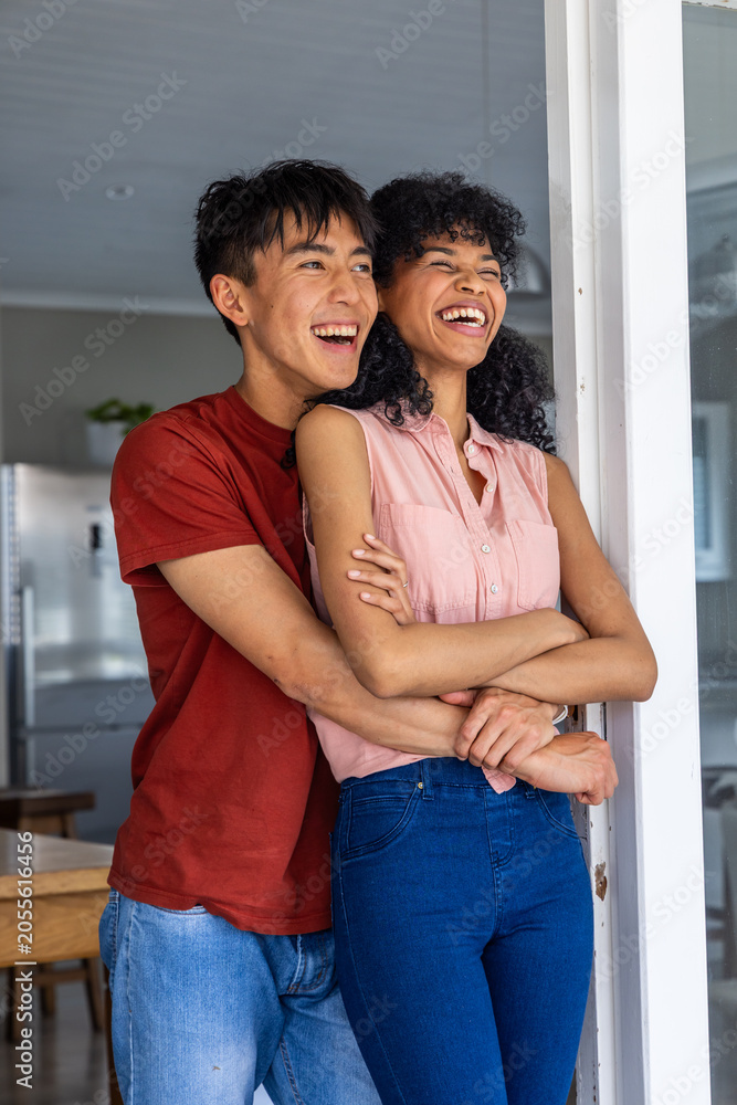 Obraz premium Vertical video: Partner wrapping arms, couple laughing at kitchen door near fridge in red and pink