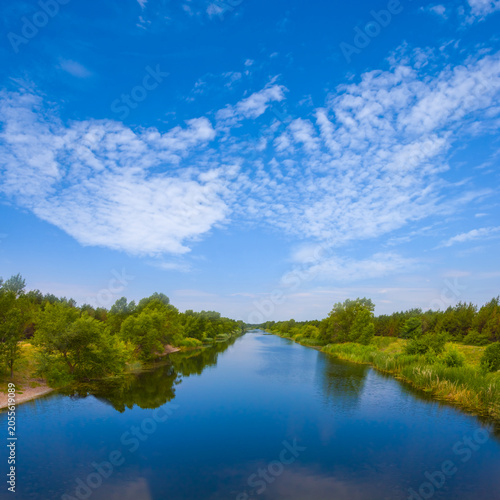 calm river with forest on coast under blue cloudy sky