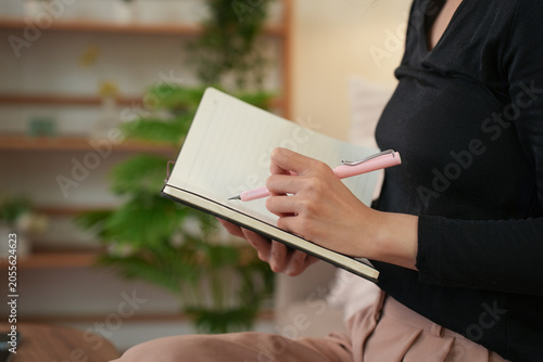 Close Up of Woman Writing in Notebook on Sofa