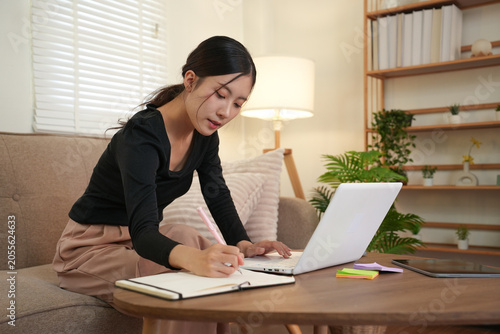 Woman Organizing Papers While Using Laptop at Home