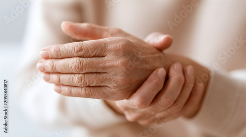 Senior woman with painful hands suffering from arthritis. Elderly person holding aching inflamed joint. Chronic disease, healthcare issue, geriatric medicine and body pain concept.