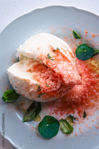 Fresh buffalo mozzarella with grated frozen tomato and herbs, gourmet Italian summer recipe 