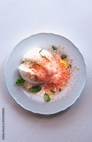Fresh buffalo mozzarella with grated frozen tomato and herbs, gourmet Italian summer recipe 