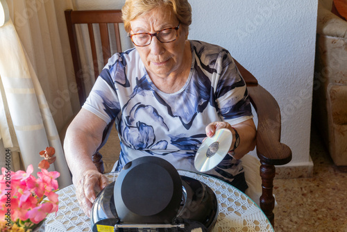 Senior woman preparing to listen to a CD on a vintage stereo system