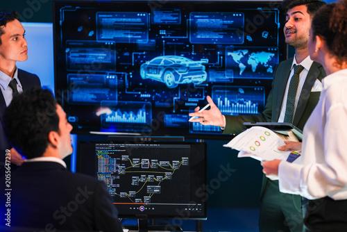 Obraz na plátně Engineering team discussing AI-driven robotic vehicle path planning and performance telemetry in a high-tech control center