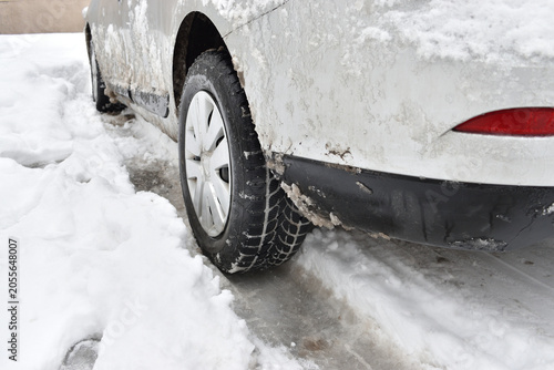 Vehicle wheel partially covered by snow during winter weather.