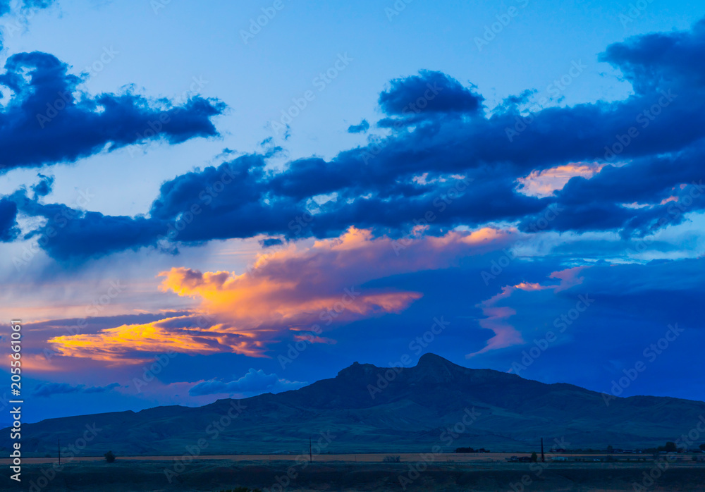 Naklejka premium Blue hour photography includes sunset scenes with Heart Mountain near Cody, Wyoming, USA.. Rolling clouds show orange glow with deep blue beauty.