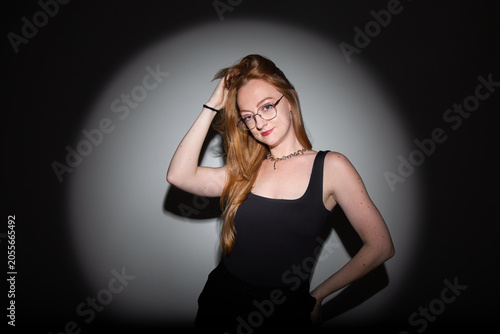 fotografia em estúdio, editorial de moda, modelo branca com cabelos ruivos longos, roupa preta, pose moderna com estética dramática iluminação focal com sombras marcadas