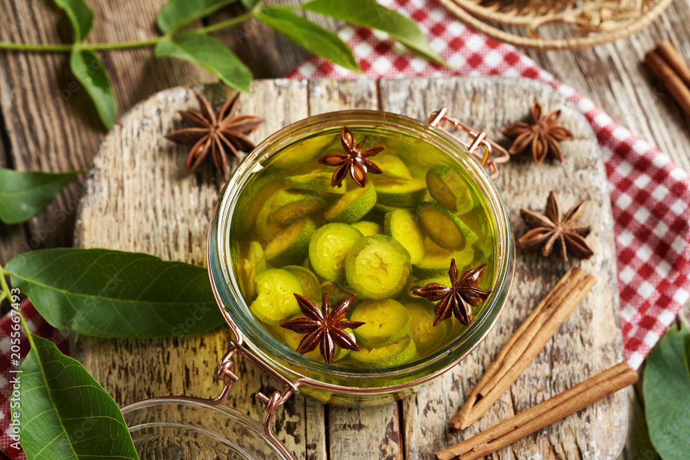 Naklejka premium Preparation of homemade nut liqueur or tincture from green unripe walnuts and spices