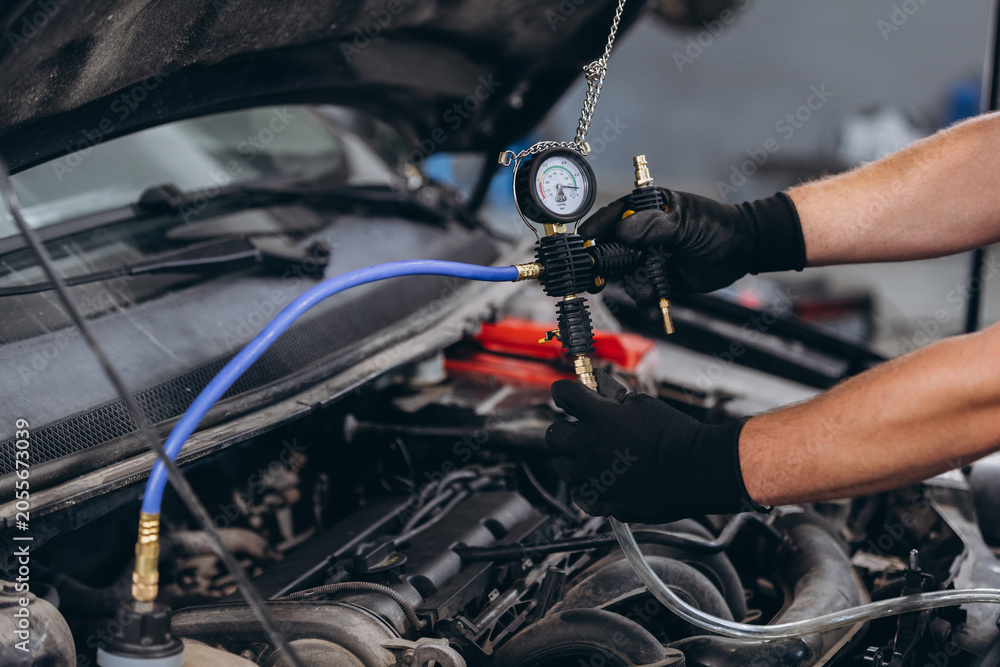 Fototapeta premium Mechanic checking car engine pressure using diagnostic tool