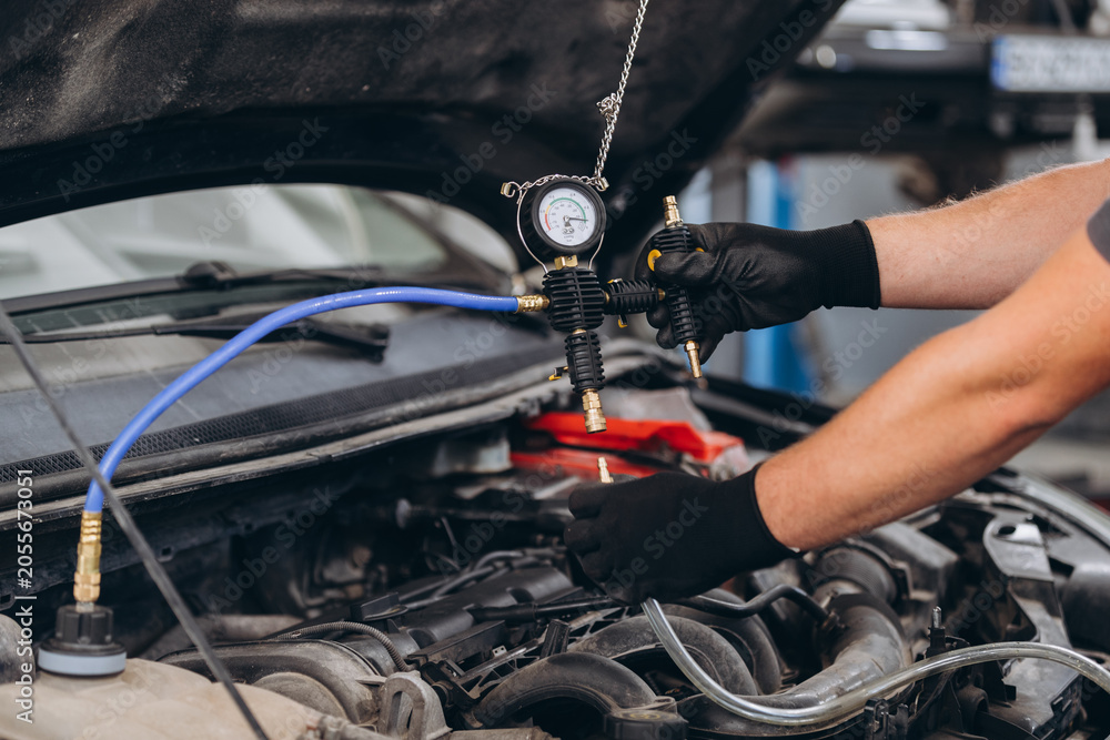 Fototapeta premium Mechanic diagnosing car engine cooling system pressure