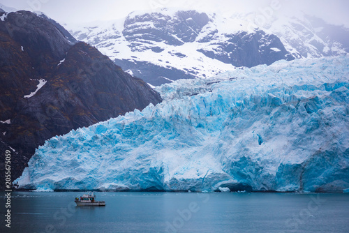 small boat in front of large glacier in kenai fjords national park